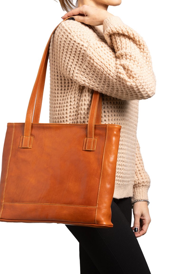 Borsa tote in pelle marrone con due manici robusti, forma rettangolare, texture liscia e cuciture a contrasto. Indossata sotto il braccio.