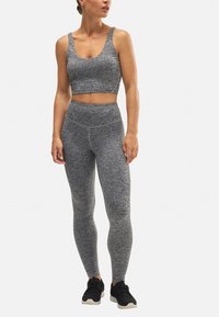 Top corto atlético gris y mallas de cintura alta hechas de tela texturizada, combinadas con zapatillas negras. Presenta un ligero patrón jaspeado.