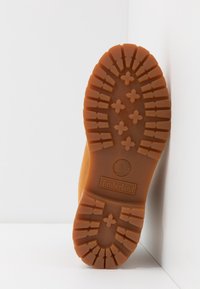 Semelle en caoutchouc d'une botte Timberland beige affichant des crampons profonds et texturés conçus pour l'adhérence et la durabilité.