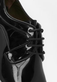 Zwarte gepatineerde leren dresschoenen met een ronde neus, voorzien van een gepolijste afwerking, decoratieve stiksels en zwarte veters door de oogjes.