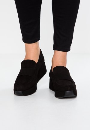 Czarne zamszowe loafersy na platformie z okrągłym noskiem i płaską, gumową podeszwą. Posiadają szeroki górny panel oraz detale w postaci przeszyć.