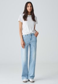 Lichtblauwe wijde spijkerbroek van denim, voorzien van een klassieke vijf-pocketdesign en metalen hardware, gecombineerd met een plain wit katoenen t-shirt.