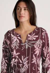 Langsleeve maroon top met een V-hals, voorzien van een palmblad- en maanpatroon in roze en grijs, met een gladde textuur en een ontspannen pasvorm.