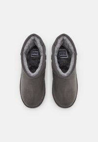 Stivaletti alla caviglia in suede grigio con una morbida fodera in pelliccia e dettagli cuciti. L'interno presenta un logo su un'etichetta di tessuto.