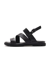 Black leather sandal featuring three strap design, adjustable buckle, and a textured sole with a flat shape. Minimalist and functional construction.