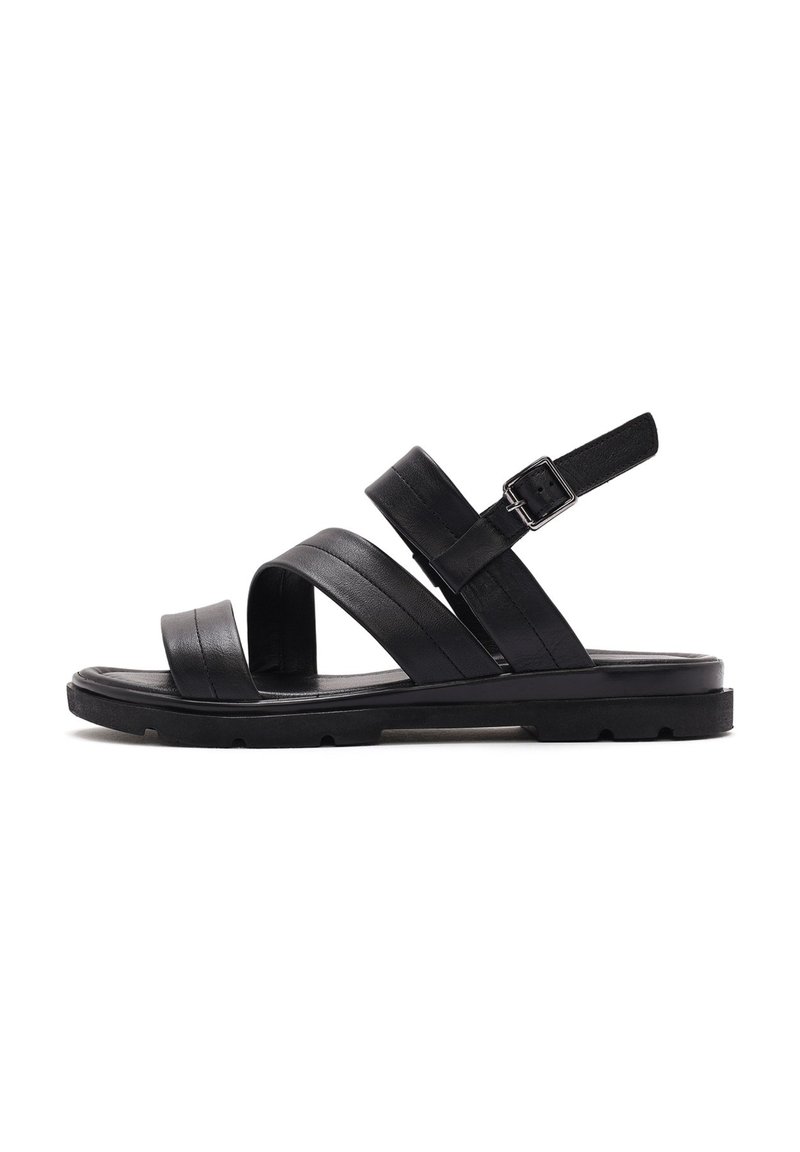 Black leather sandal featuring three strap design, adjustable buckle, and a textured sole with a flat shape. Minimalist and functional construction.
