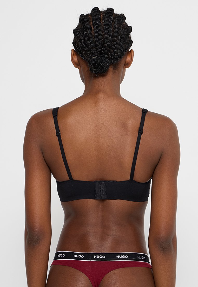 Schwarzer kabelloser BH mit verstellbaren Trägern und Hakenverschluss. Das Material wirkt glatt und hat ein minimalistisches Design.