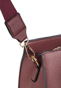 Sac en bandoulière en cuir bourgogne avec une finition texturée, doté d'un fermoir en métal doré et de coutures accentuées sur une large sangle bourgogne.