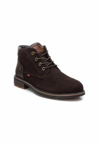 Botas de ante marrón hasta el tobillo con puntera redonda, ojales dorados y un acento de cuero marrón cerca de la parte superior. Suela de goma con detalles en beige.