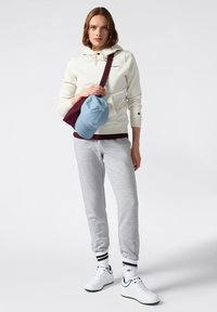 Crème hoodie met drawstring, grijze sweatpants, blauwe pet en witte sneakers met groene accenten. Minimalistisch ontwerp, casual activewear stijl.