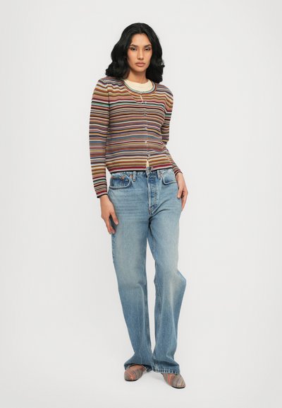 Cardigan multicolore a righe con bottoni, abbinato a jeans a gamba larga azzurri e mocassini in fantasia. Materiale in maglia liscia con texture a coste.