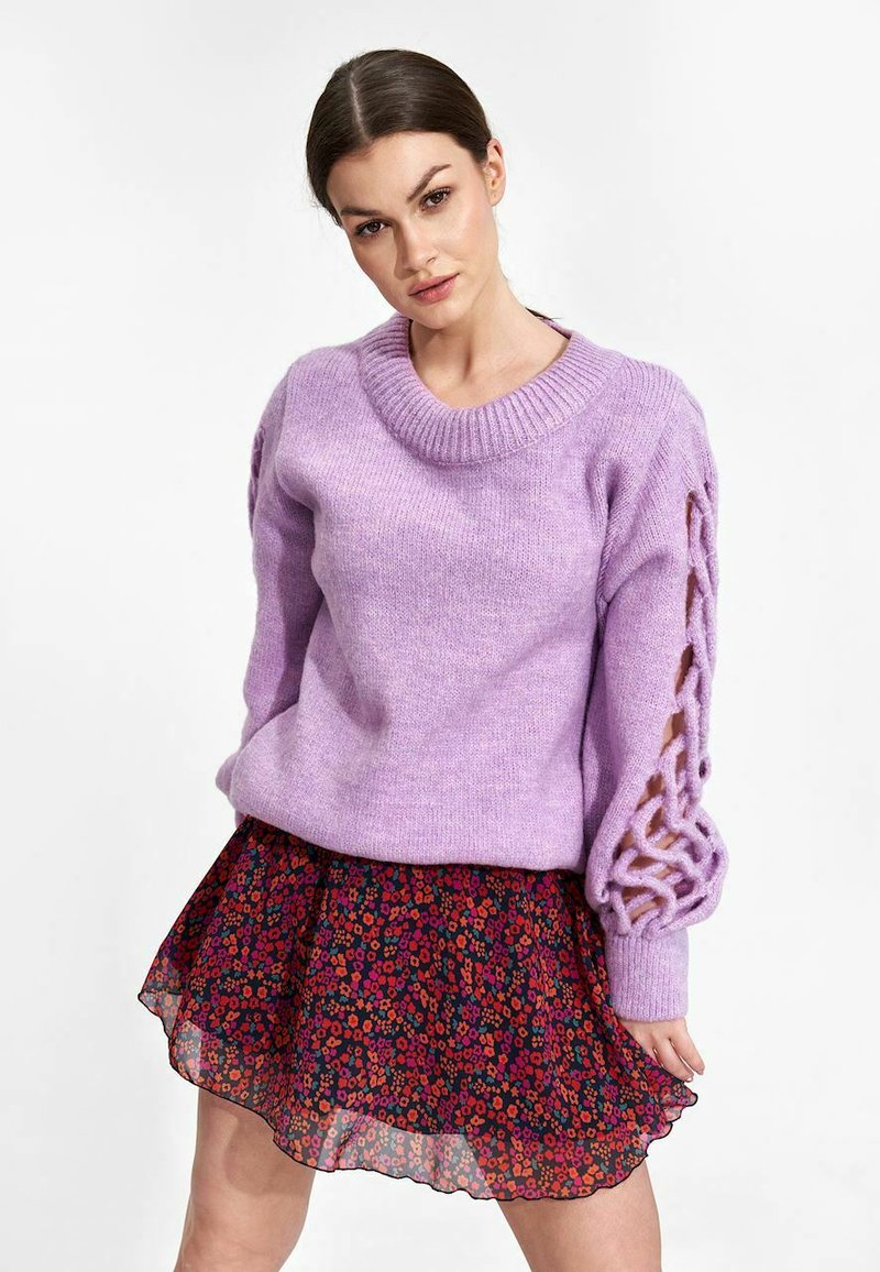 Lila gebreide trui met een brede ronde halslijn en uitsnijdingen op de mouwen, gecombineerd met een bloeiende, gelaagde rokken met ruches.