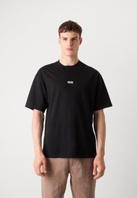 T-shirt in cotone nero con collo rotondo e maniche corte. Presenta un piccolo logo rettangolare bianco del marchio sul petto.
