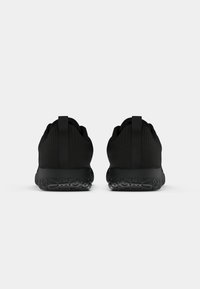 Svarta sportskor med en texturerad tygöverkonstruktion, rund tå, vadderad krage och slitstark gummisula med ett mönstrat mönster.