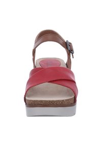 Red leather sandal with crossover straps, brown ankle strap featuring a buckle, and a cushioned cork footbed on a white platform sole.
