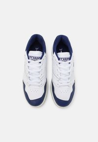 Fehér sneaker, tengerészkék részletekkel, sima bőr felső résszel, perforált részletekkel és párnázott béléssel a kényelem érdekében.