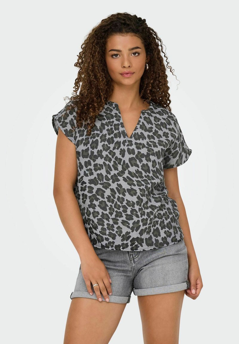 Grå kortærmet top med leopardmønster, der har en V-hals og en afslappet pasform, parret med rullede denimshorts.
