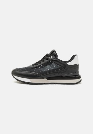 Black sneaker with a dotted pattern, leather and mesh upper, padded collar, and white accents. Features a gray midsole and textured rubber sole.