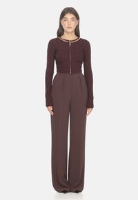 Completo bordeaux a due pezzi composto da una giacca cropped con texture e zip a catena dorata, e pantaloni a vita alta con gamba larga.