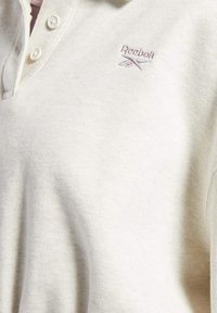 Weißes Baumwoll-Polohemd mit einer Dreiknopf-Leiste und dezentem Reebok-Logo in Helllila auf der Brust. Weiches, strukturiertes Material.