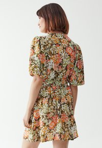 Floral dress with puffed sleeves, featuring a brown background with white, orange, and green flowers. Gathered waist and flared skirt.
