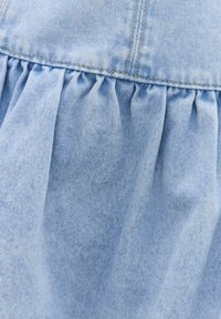 Tissu denim bleu clair avec un détail de couture froncée créant de doux plis sous une couture à double piqûre.