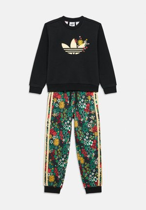 Black sweatshirt with floral Adidas logo and matching floral-patterned jogger pants with yellow side stripes and ribbed cuffs.