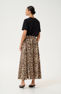 Haut noir à manches courtes associé à une jupe longue imprimée léopard, dotée d'une taille élastique et d'une texture douce et fluide. Mules noires à talons.
