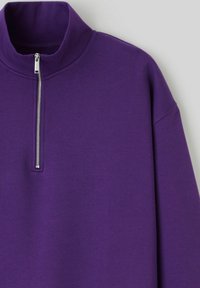 Pull-over à col montant violet avec une fermeture éclair argentée. Confectionné dans un matériau doux, avec des manches longues et une coupe décontractée. Aucun motif ni accent visible.