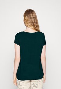 Ciemnozielona koszulka z krótkim rękawem, z dekoltem w serek, wykonana z miękkiego materiału, o luźnym kroju, pokazana od tyłu, z gładką fakturą i bez wzorów.