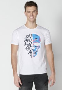 White cotton t-shirt featuring a graphic of a blue and pink skull with the text "DO YOU FEEL RE-AI?" printed in bold black lettering.