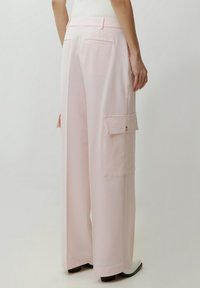 Rosa weite Cargo-Hosen mit glatter Textur, ausgestattet mit großen Seitentaschen, Gesäßtaschen und einem lässigen Schnitt.