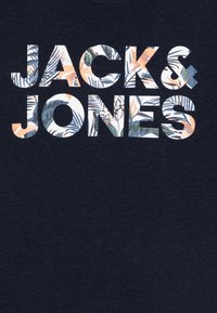 T-shirt bleu marine avec le texte "JACK & JONES" en gras, police blanche, rempli d'un motif floral multicolore.