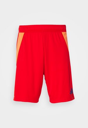 Shorts de sport rouges avec une taille élastique, dotés de panneaux latéraux orange et d'un logo bleu en bas à gauche. Fini textile lisse.