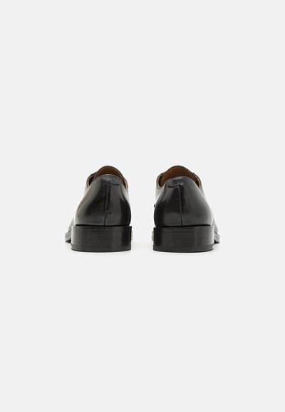 Scarpe eleganti in pelle nera con finitura liscia, punta rotonda e tacco basso a blocco. Presentano cuciture minime e leggere accentuazioni a intaglio.