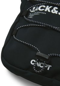 Zwarte rugzak van textuurstof, met een opvallend wit logo, verstelbaar bungee koord met zwart-wit patroon en kunststof toggles.