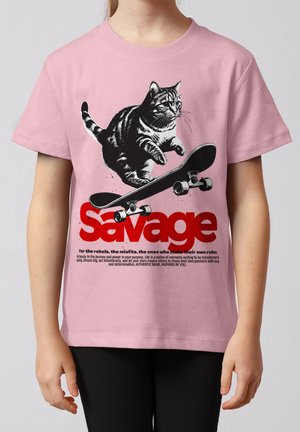 Kind trägt pinkes Shirt mit Grafik einer Katze, die über ein Skateboard springt, über dem fettgedruckten roten Wort "Savage" und kleinem motivierendem Text darunter.