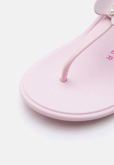 Κοντινή λήψη ενός ανοιχτό ροζ σανδαλιού τύπου σαγιονάρας με υφή στη σόλα και διακόσμηση με λουλούδι στο λουράκι.