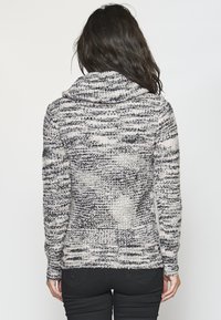 Pull en tricot noir et blanc avec un col bénitier, doté d'un motif mouliné texturé. Manches longues et silhouette cintrée.