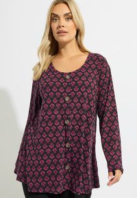 Maglietta a maniche lunghe in tessuto scuro con motivo floreale rosa, scollatura rotonda e chiusura a bottoni. Presenta una vestibilità comoda e una trama testurizzata.