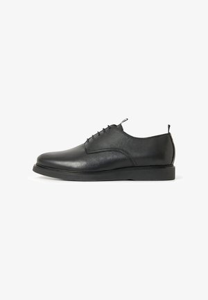 Black leather dress shoe with rounded toe, lace-up design, flat rubber sole, and a smooth finish. Features a small pull tab at the rear.