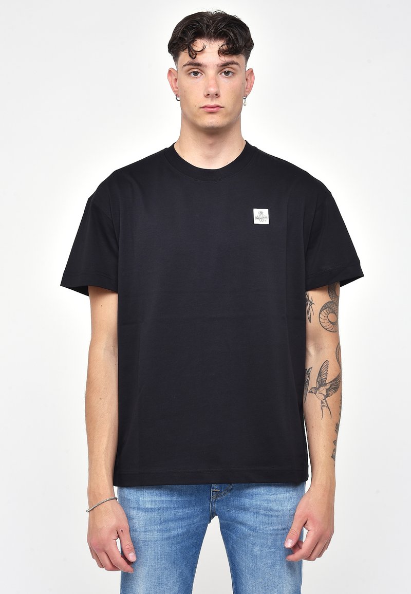 Mustat puuvillapaidat, joissa on pyöreä pääntie ja lyhyet hihat. Vasemmassa rintataskussa on pieni neliölogo.