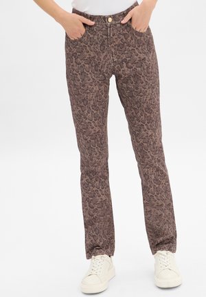 Leopardenmuster-Hosen in Brauntönen, aus weichem Stoff, mit Slim-Fit, vorderen Taschen und einem Knopfverschluss, kombiniert mit weißen Sneakers.
