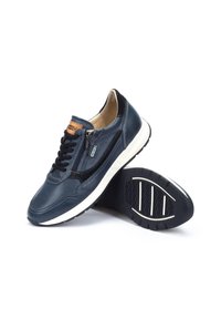 Námořnické modré kožené tenisky s perforovanou texturou, s bílou podrážkou, černým šněrováním vpředu, zipovým uzávěrem a semišovými akcenty.