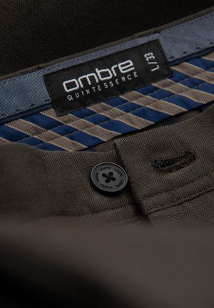 Ombre gemerkt donkerbruin stof met een zwart knoopdetail, voorzien van een gestreepte blauwe en beige accent aan de binnenkant.