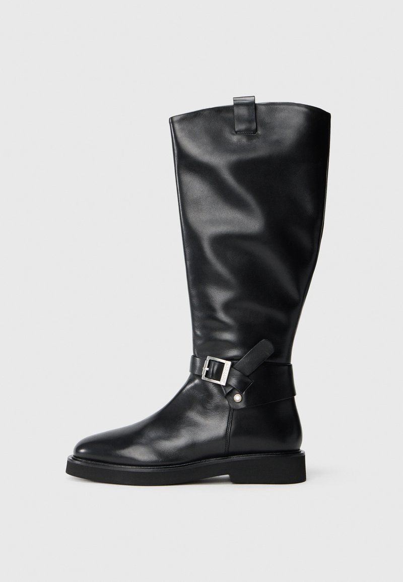 Black leather knee-high boot with a low heel and silver buckle strap detail around the ankle, set against a plain background.