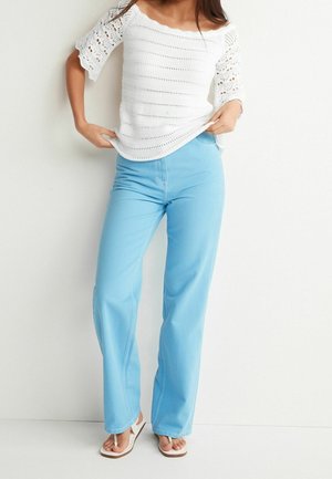 Light blue wide-leg jeans paired with a white crocheted off-shoulder top, featuring intricate patterns and a casual design.