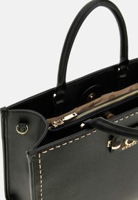 Zwarte faux leren handtas met gouden hardware, dubbele bovenhandgrepen en zichtbare stiksels. Voorzien van een ritscompartiment en merkembleem.