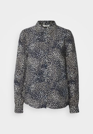 Mornarska bluza s prednjim dugmadi, dugim rukavima i točkasti uzorak u pan tonovima. Izrađena od glatkog materijala s laganim sjajem.