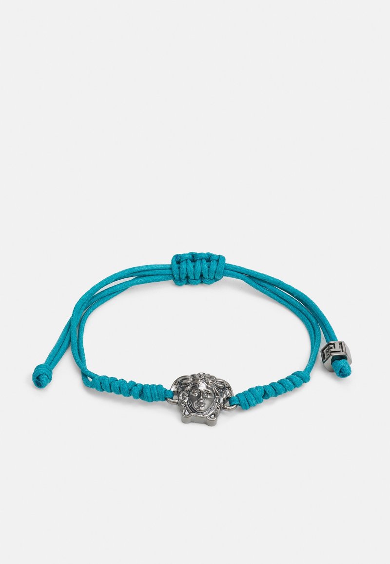 Bracelet en corde turquoise avec un charm en forme de tête de lion en argent, finement détaillé, doté d'une fermeture ajustable par nœud coulissant.